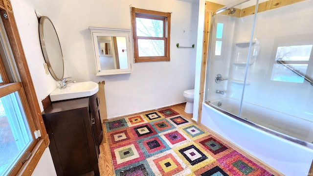 full bathroom with bath / shower combo with glass door, vanity, and toilet