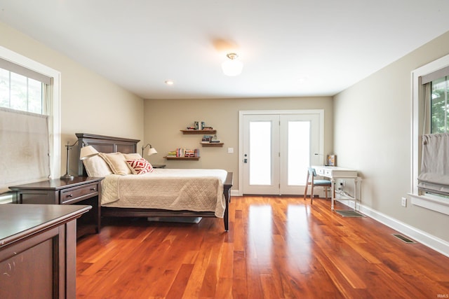 bedroom featuring multiple windows and dark hardwood / wood-style flooring