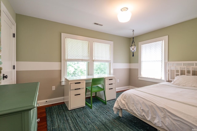 bedroom with multiple windows and dark hardwood / wood-style floors