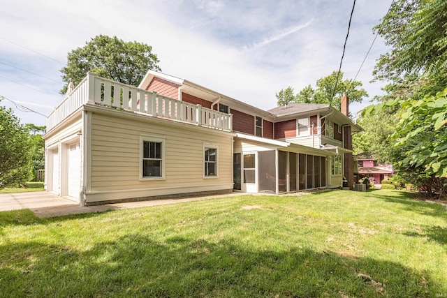 rear view of property featuring a garage, a balcony, a lawn, cooling unit, and a sunroom