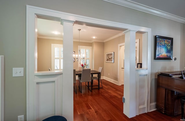 corridor with ornate columns, ornamental molding, a notable chandelier, and dark hardwood / wood-style flooring