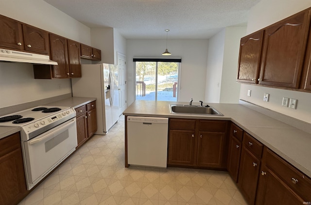 kitchen featuring pendant lighting, sink, white appliances, and kitchen peninsula