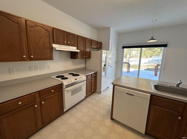 kitchen featuring white appliances, decorative light fixtures, sink, and a textured ceiling