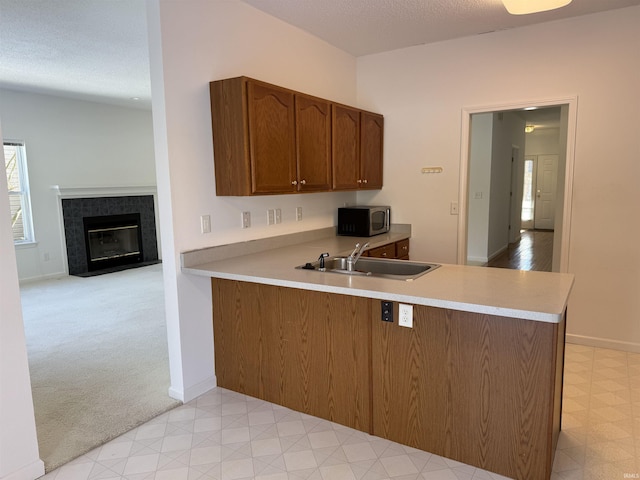 kitchen featuring sink, light carpet, a textured ceiling, and kitchen peninsula