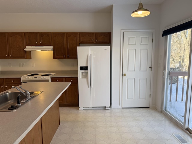 kitchen with electric stove, white refrigerator with ice dispenser, sink, and hanging light fixtures