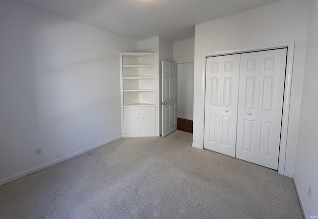 unfurnished bedroom featuring light colored carpet, a closet, and a textured ceiling