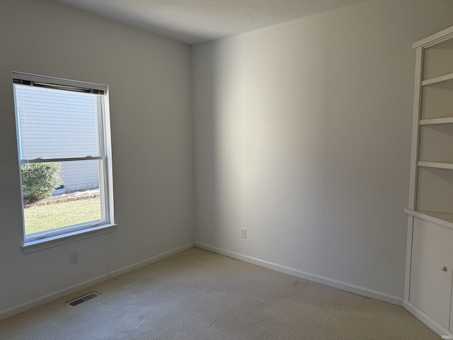 carpeted spare room with a textured ceiling