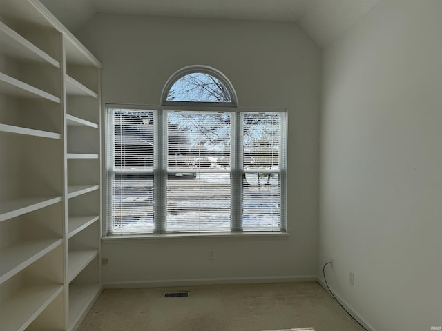 carpeted empty room featuring vaulted ceiling