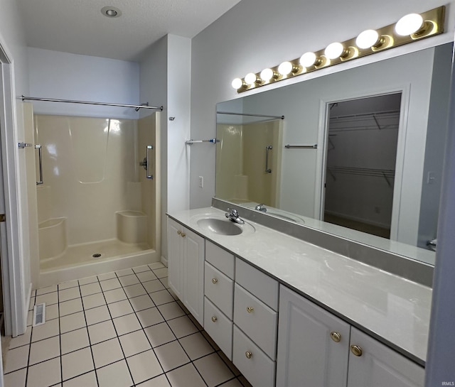 bathroom featuring tile patterned flooring, vanity, and a shower