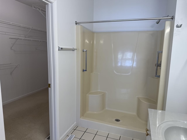 bathroom featuring tile patterned flooring, a shower, and vanity