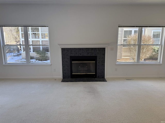 unfurnished living room featuring a tiled fireplace and carpet flooring