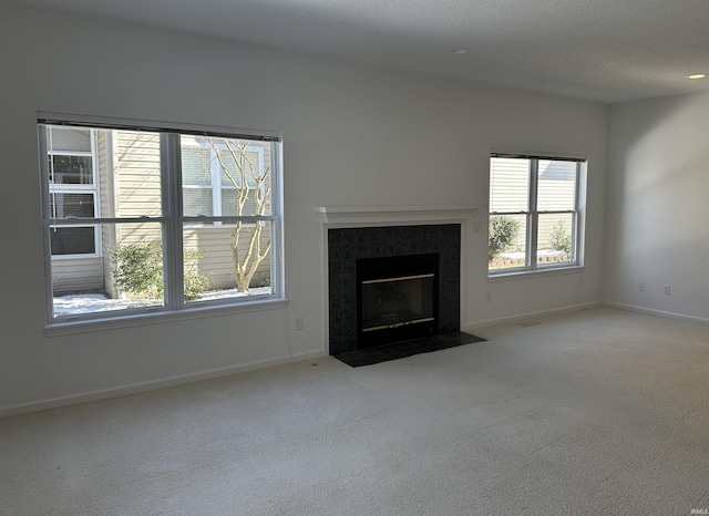 unfurnished living room with light colored carpet, a fireplace, and a textured ceiling