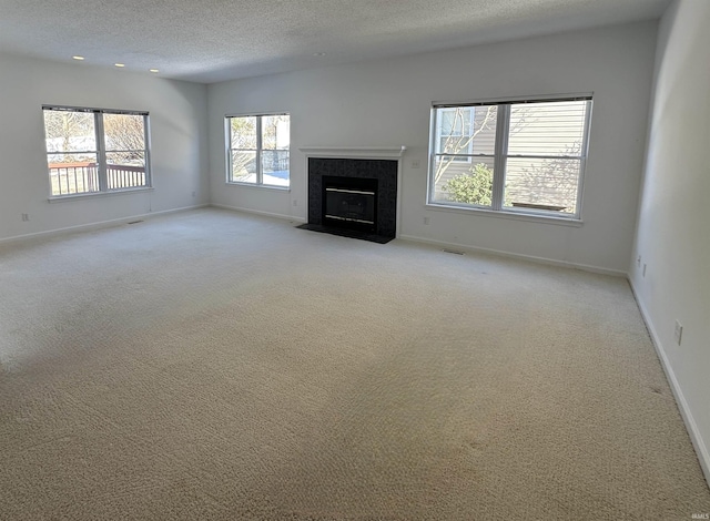 unfurnished living room with light carpet, a fireplace, and a textured ceiling