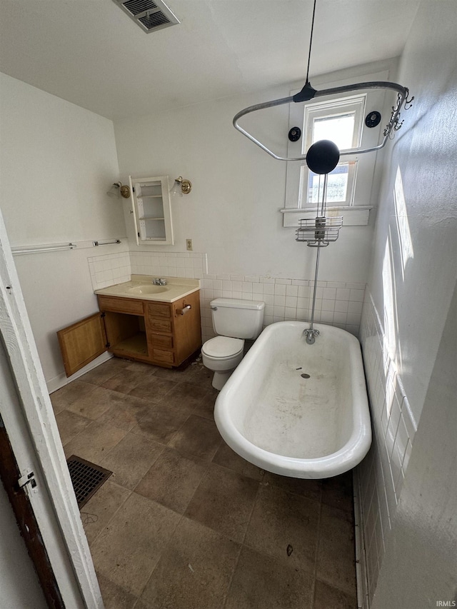 bathroom with a bathing tub, tile walls, vanity, and toilet