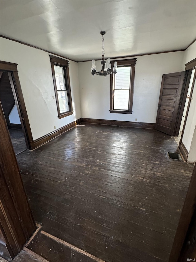 unfurnished dining area featuring crown molding, dark hardwood / wood-style flooring, and a notable chandelier