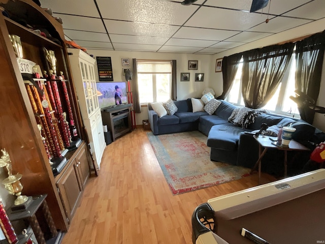 living room with a paneled ceiling and light wood-type flooring