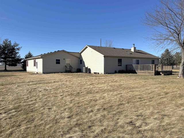 rear view of house featuring a wooden deck and a yard