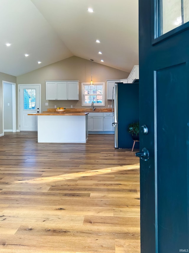 kitchen with white cabinetry, butcher block counters, and stainless steel fridge