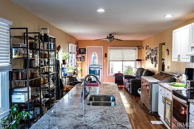 kitchen featuring white cabinetry, sink, light stone countertops, dark wood-type flooring, and stainless steel electric range