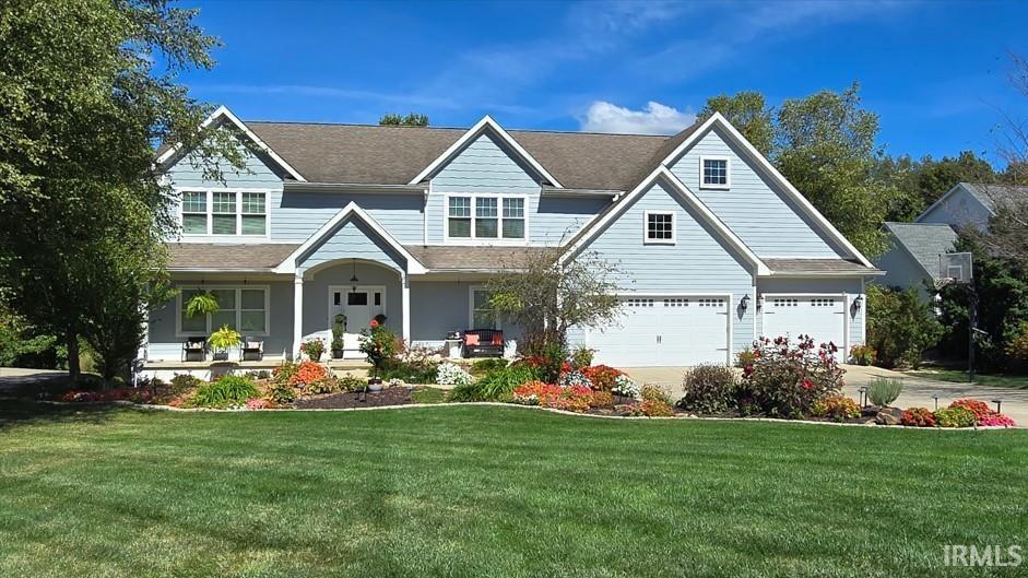 view of front of property with a garage, a front lawn, and covered porch