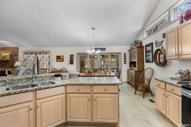 kitchen with sink, hanging light fixtures, light stone counters, light brown cabinetry, and vaulted ceiling