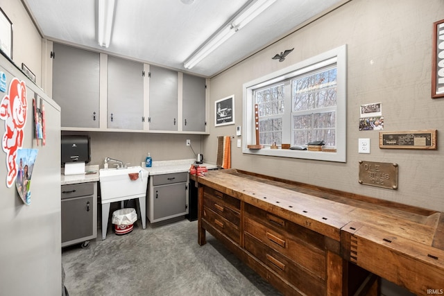 kitchen featuring fridge, sink, concrete floors, and gray cabinetry