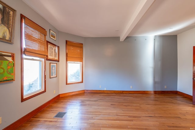 spare room featuring beam ceiling and light wood-type flooring