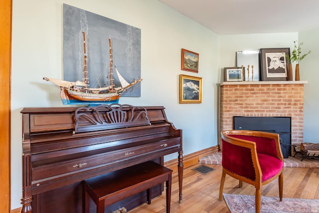 living area featuring a brick fireplace and light hardwood / wood-style floors