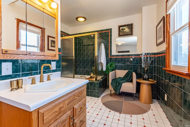 bathroom with vanity, tile patterned flooring, a shower with door, and tile walls