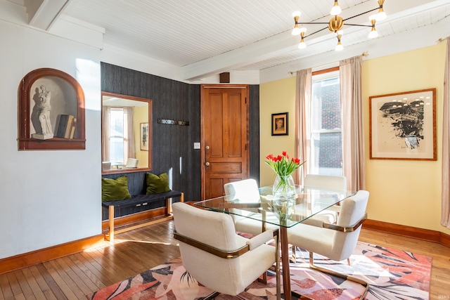 dining space with an inviting chandelier, beam ceiling, and hardwood / wood-style floors