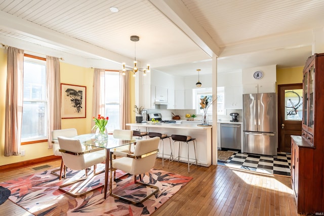 dining space featuring an inviting chandelier, beam ceiling, and light hardwood / wood-style floors