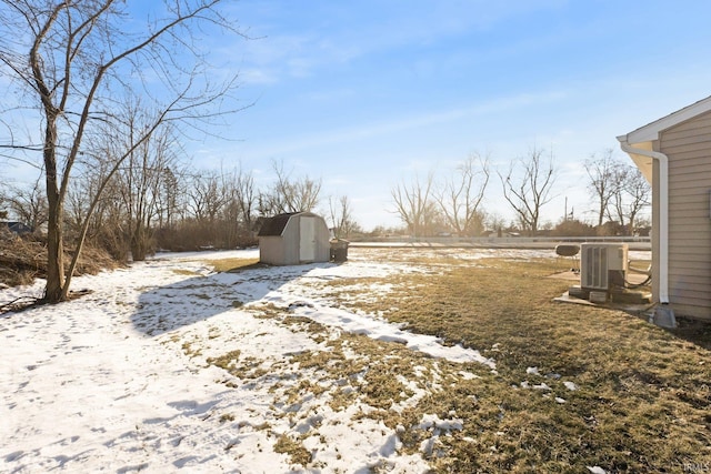 snowy yard featuring a shed and central AC unit