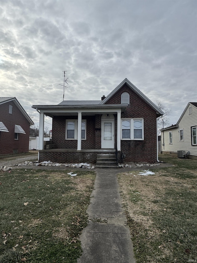 bungalow-style house featuring a front yard, central air condition unit, and covered porch