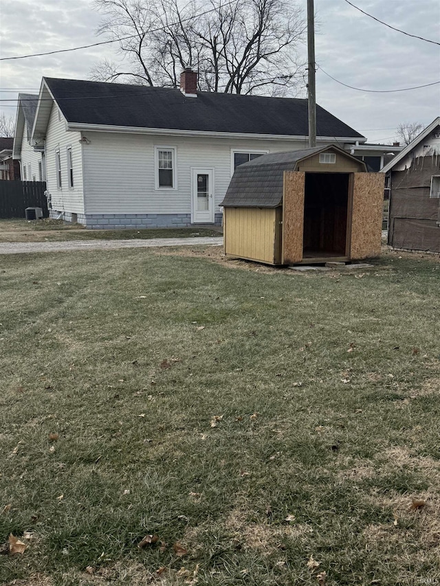 rear view of property featuring a shed and a lawn