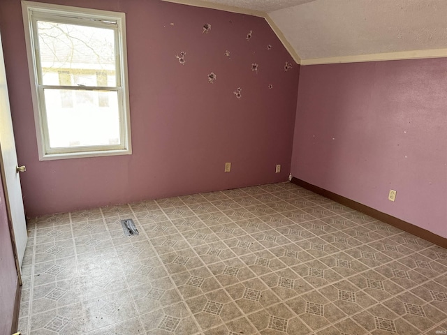 bonus room featuring lofted ceiling and a textured ceiling