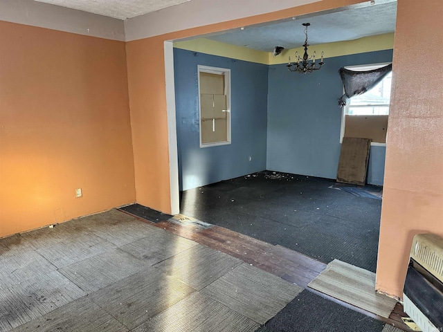 unfurnished room with dark wood-type flooring, heating unit, and a notable chandelier