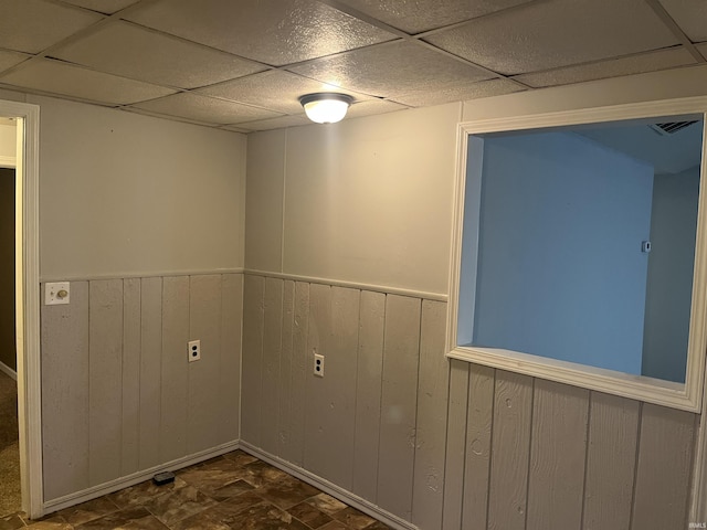 interior space featuring a paneled ceiling and wood walls