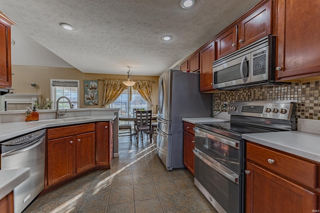 kitchen with sink, a textured ceiling, hanging light fixtures, appliances with stainless steel finishes, and backsplash