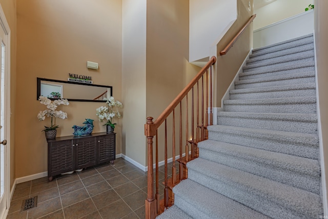 stairs with tile patterned flooring and a high ceiling