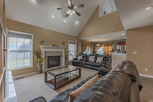 living room with ceiling fan, a tiled fireplace, high vaulted ceiling, and a wealth of natural light