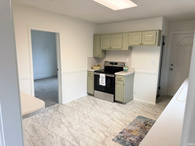 kitchen with electric stove, green cabinetry, and a drop ceiling