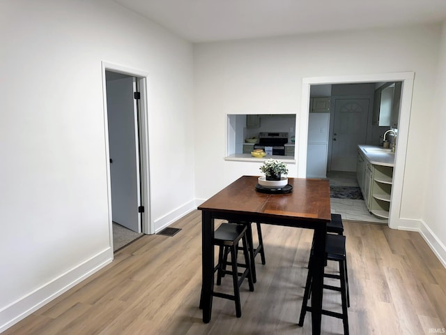 dining space with light hardwood / wood-style floors and sink