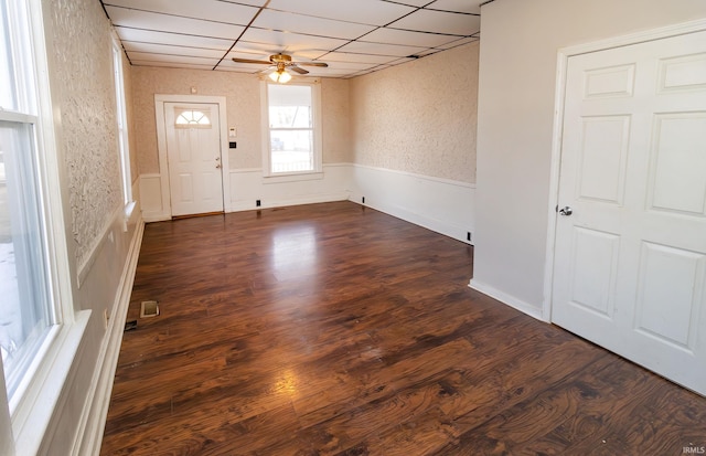 interior space featuring a drop ceiling, dark wood-type flooring, and ceiling fan