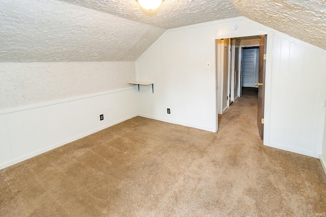 bonus room featuring lofted ceiling, light carpet, and a textured ceiling