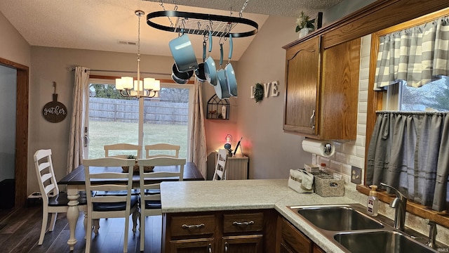 kitchen featuring an inviting chandelier, sink, dark hardwood / wood-style flooring, hanging light fixtures, and a textured ceiling