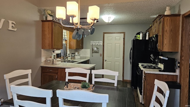 kitchen with sink, gas range, a chandelier, a textured ceiling, and decorative backsplash