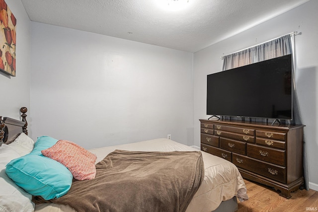 bedroom with a textured ceiling and light hardwood / wood-style flooring