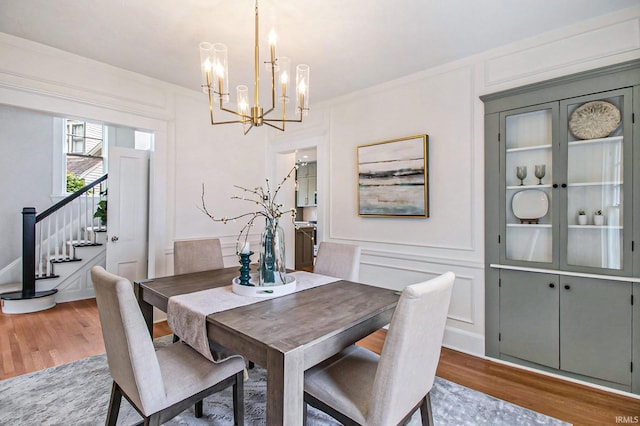 dining space with hardwood / wood-style floors, crown molding, and a chandelier