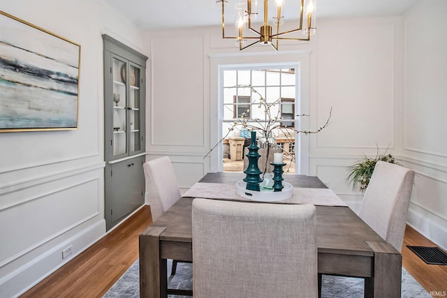 dining room with dark wood-type flooring, a chandelier, and built in shelves