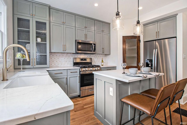 kitchen featuring gray cabinets, decorative light fixtures, tasteful backsplash, sink, and stainless steel appliances